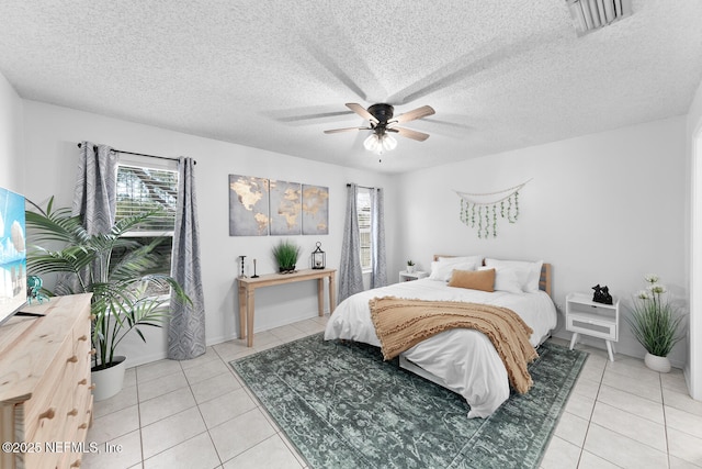 bedroom with ceiling fan, a textured ceiling, tile patterned flooring, and visible vents