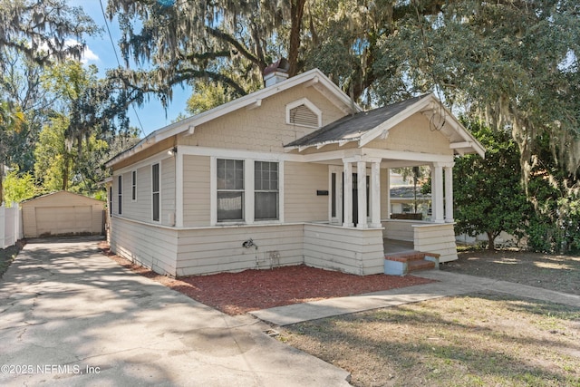 bungalow-style house featuring an outbuilding, a chimney, covered porch, and a garage