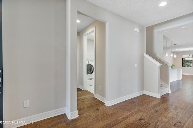 corridor featuring dark hardwood / wood-style flooring, washer / dryer, and a textured ceiling