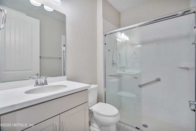 bathroom with vanity, toilet, and a shower with door