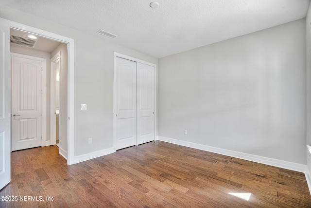 unfurnished bedroom with hardwood / wood-style flooring, a closet, and a textured ceiling