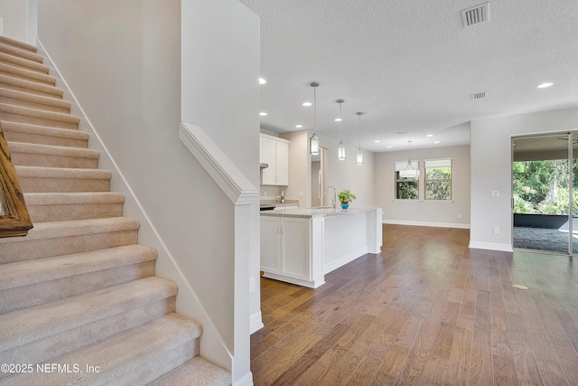 staircase featuring wood-type flooring, sink, and a textured ceiling