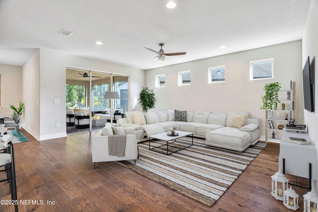 living room featuring dark hardwood / wood-style flooring, ceiling fan, and a textured ceiling