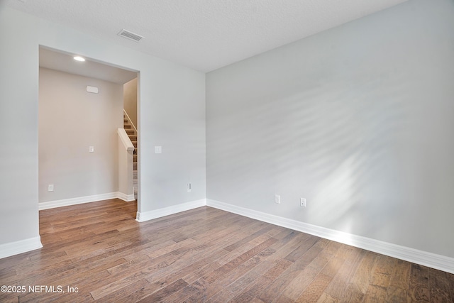 unfurnished room with wood-type flooring and a textured ceiling