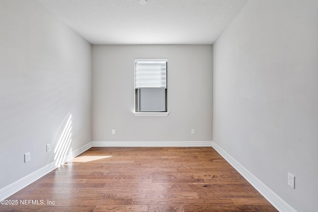 unfurnished room featuring a wealth of natural light, wood-type flooring, and a textured ceiling