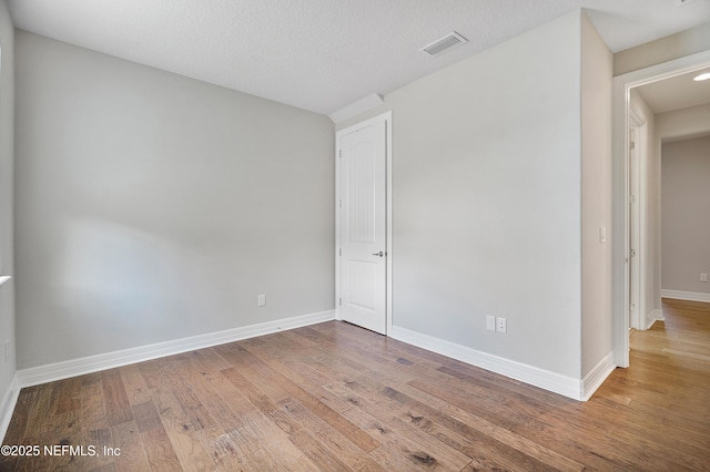 empty room with hardwood / wood-style flooring and a textured ceiling