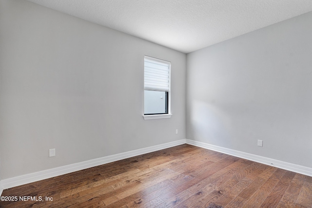 empty room featuring wood-type flooring and a textured ceiling