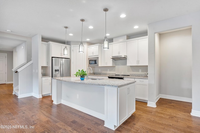 kitchen featuring sink, white cabinetry, decorative light fixtures, appliances with stainless steel finishes, and an island with sink