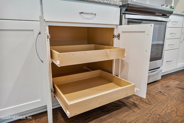 room details featuring white cabinetry, dark wood-type flooring, and electric range