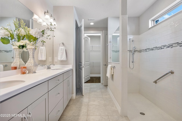 bathroom with tiled shower, vanity, tile patterned flooring, and a textured ceiling