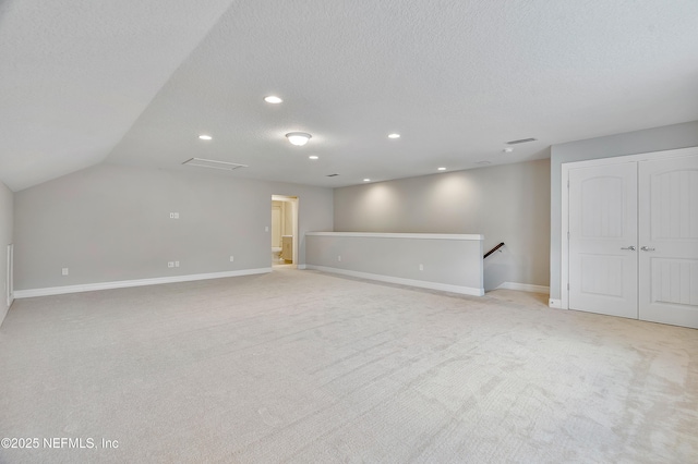 interior space featuring vaulted ceiling, light carpet, and a textured ceiling