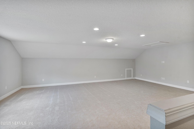 bonus room featuring lofted ceiling, light carpet, and a textured ceiling