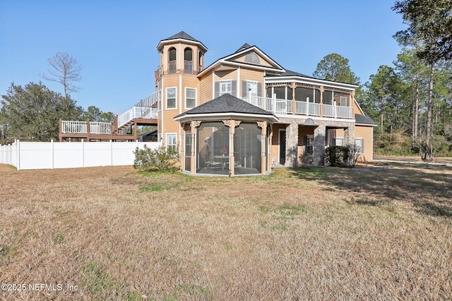 rear view of house featuring a balcony, a yard, and a sunroom