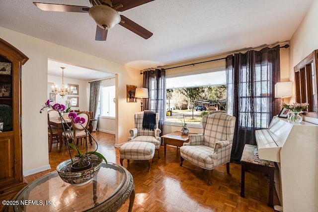 sitting room with ceiling fan with notable chandelier, parquet floors, and a textured ceiling