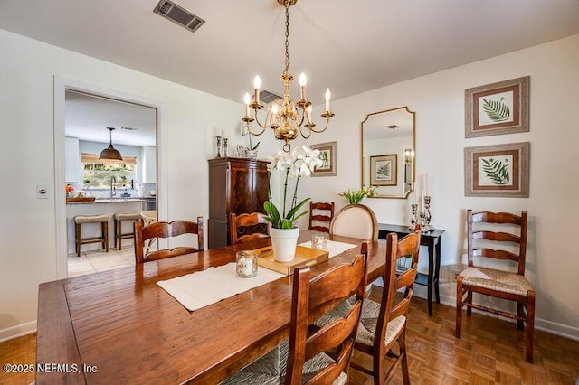 dining room with an inviting chandelier, parquet floors, and sink