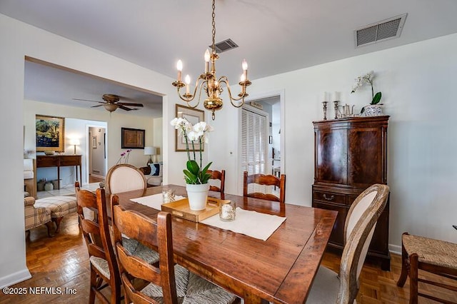 dining area with ceiling fan with notable chandelier and dark parquet floors