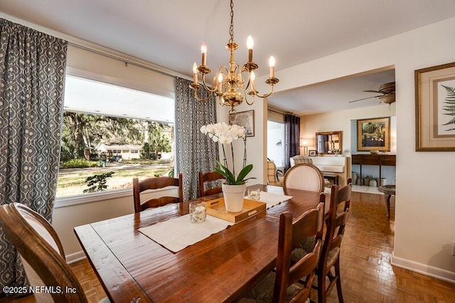 dining space featuring dark parquet flooring and ceiling fan with notable chandelier