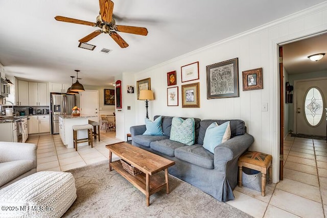 tiled living room featuring ornamental molding and ceiling fan