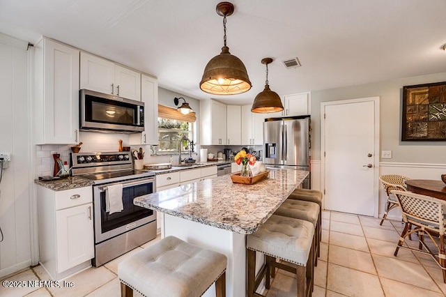 kitchen with white cabinetry, hanging light fixtures, and stainless steel appliances