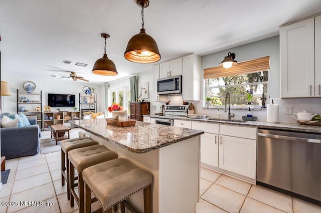 kitchen with sink, white cabinetry, decorative light fixtures, a center island, and appliances with stainless steel finishes