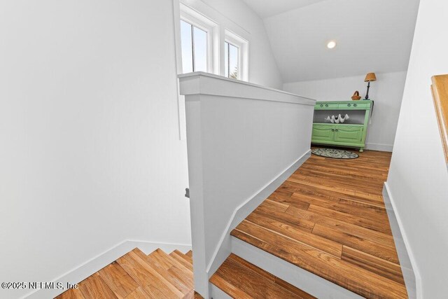 staircase featuring lofted ceiling and wood-type flooring