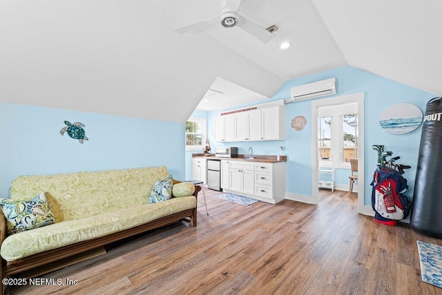 living room featuring a wall mounted air conditioner, lofted ceiling, sink, ceiling fan, and light wood-type flooring