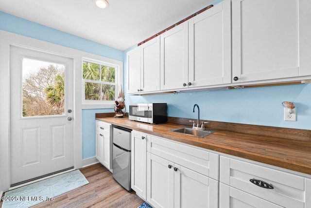 kitchen with butcher block counters, sink, white cabinetry, and fridge