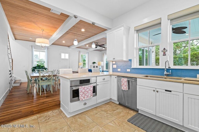 kitchen with sink, decorative light fixtures, appliances with stainless steel finishes, kitchen peninsula, and white cabinets