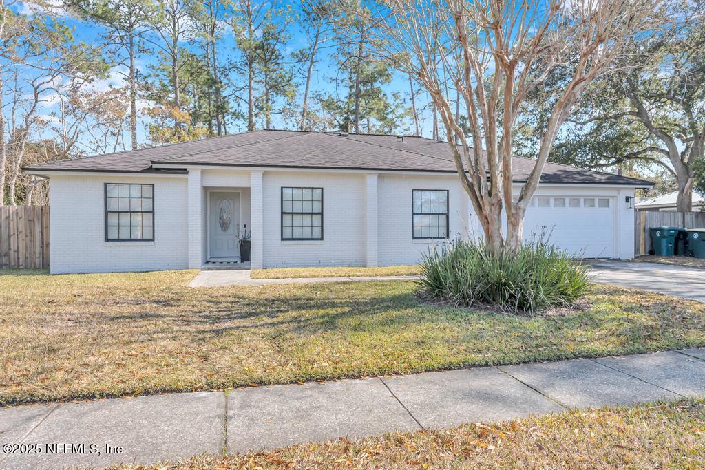 ranch-style house with a garage and a front lawn