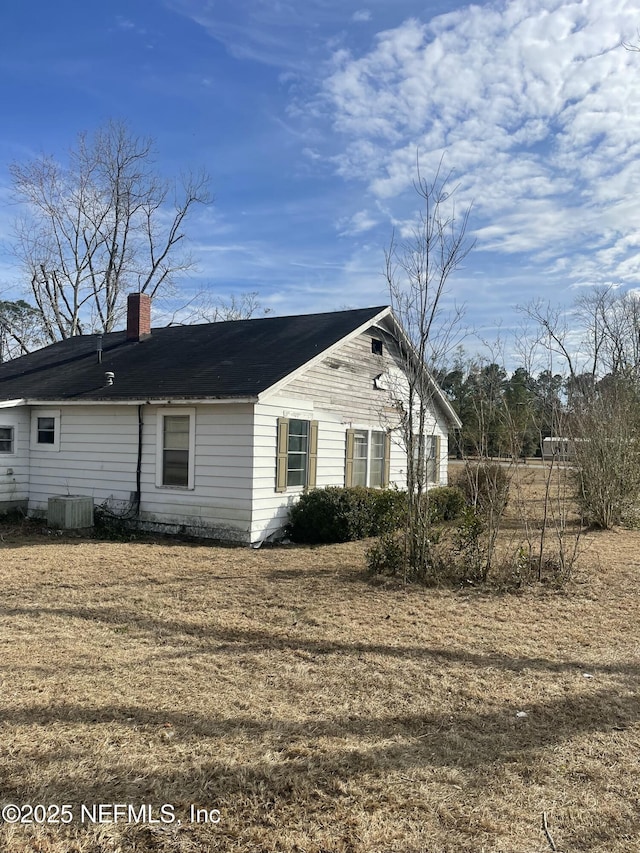 view of side of property with a yard and central air condition unit