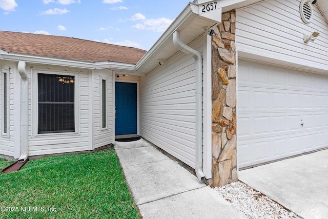 entrance to property featuring a garage and roof with shingles