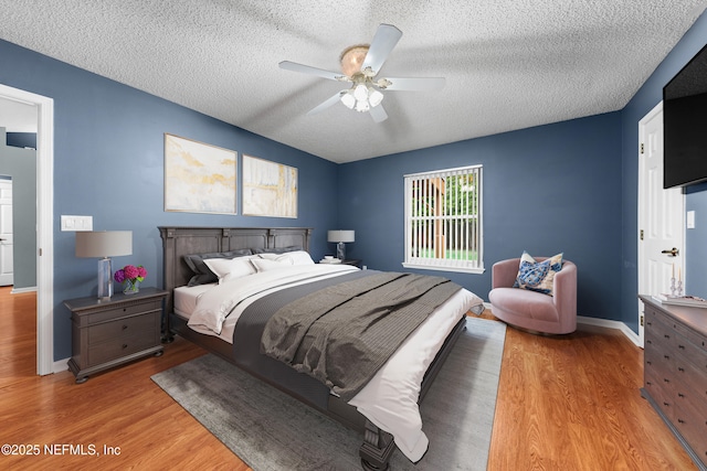 bedroom featuring baseboards, a textured ceiling, and light wood finished floors