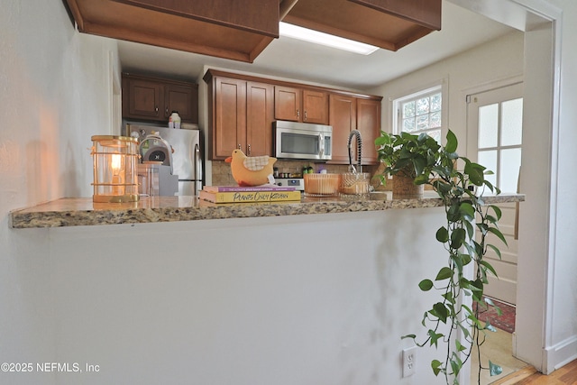 kitchen with light stone countertops, appliances with stainless steel finishes, and backsplash