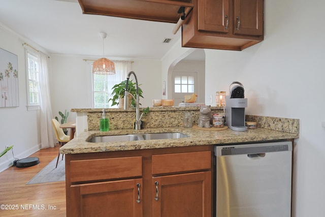 kitchen featuring decorative light fixtures, dishwasher, sink, light hardwood / wood-style floors, and light stone countertops