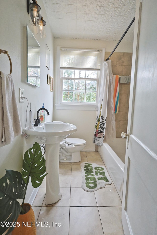 bathroom featuring tile patterned floors, toilet, and shower / bath combo with shower curtain