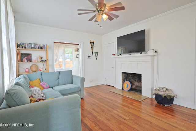 living room with hardwood / wood-style flooring, ceiling fan, ornamental molding, and a brick fireplace