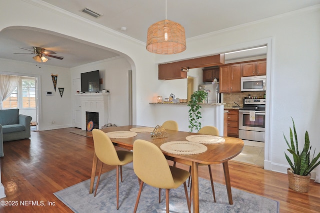 dining room featuring hardwood / wood-style floors, ornamental molding, and ceiling fan