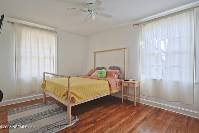 bedroom featuring multiple windows, dark wood-type flooring, and ceiling fan