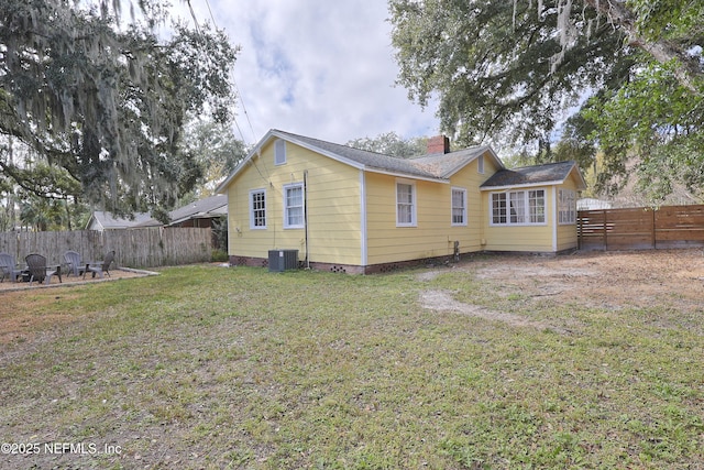 rear view of house featuring central AC and a lawn