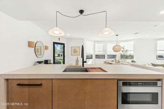 kitchen with pendant lighting, sink, plenty of natural light, and stainless steel oven