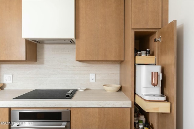 kitchen featuring black electric cooktop, oven, and backsplash