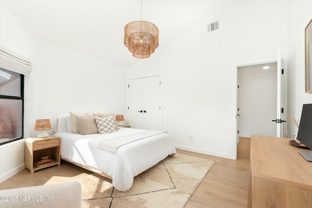 bedroom with high vaulted ceiling, light hardwood / wood-style floors, and a closet