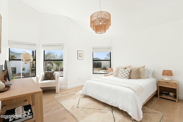 bedroom featuring high vaulted ceiling, multiple windows, and light wood-type flooring