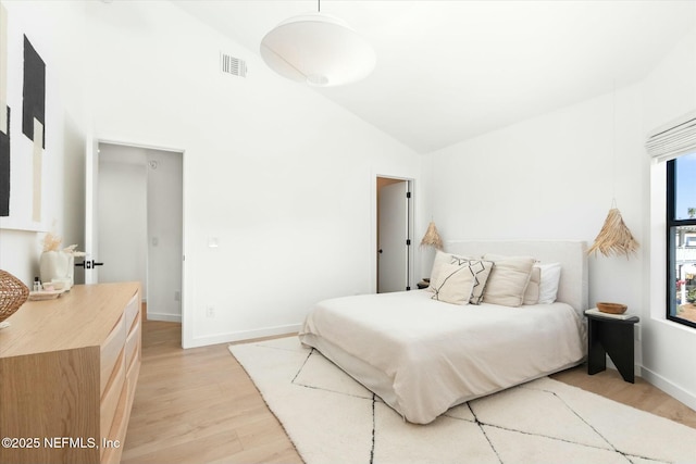 bedroom with high vaulted ceiling and light hardwood / wood-style flooring