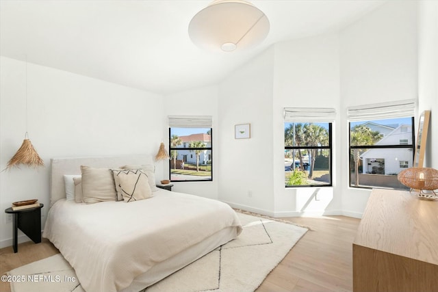 bedroom featuring high vaulted ceiling and light wood-type flooring