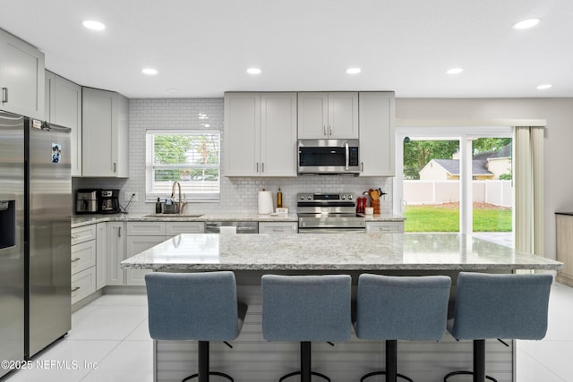 kitchen with a kitchen island, appliances with stainless steel finishes, sink, and a breakfast bar area