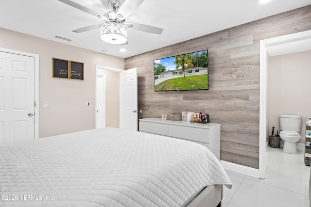 bedroom with ceiling fan, light tile patterned floors, and wooden walls