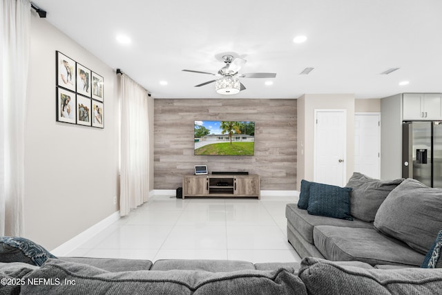 living room with light tile patterned flooring, ceiling fan, and wood walls