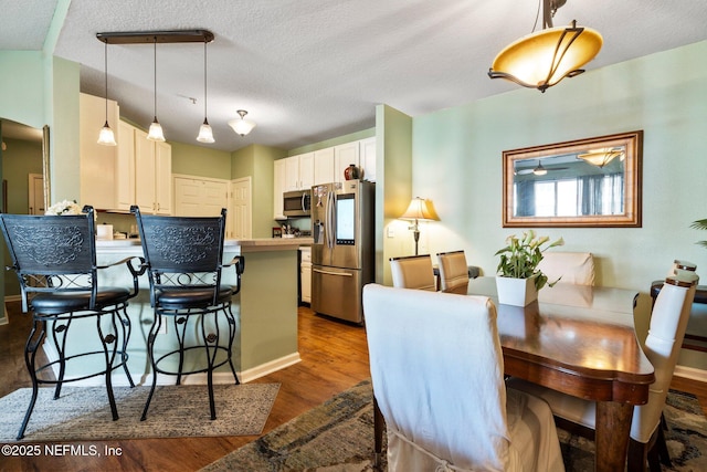 dining space with dark hardwood / wood-style floors and a textured ceiling