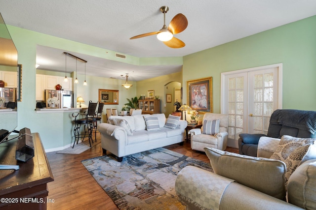 living room with dark hardwood / wood-style floors, a textured ceiling, ceiling fan, and french doors